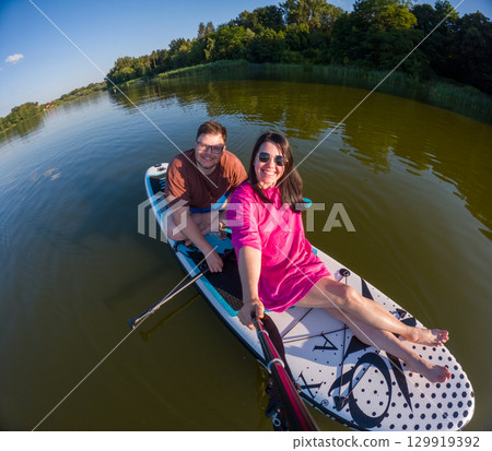 Couple Paddleboarding on a Serene Lake 129919392