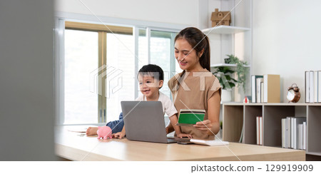 Mother and child exploring digital finance together with piggy bank 129919909