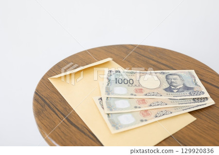 木桌上放著一個信封和三千日圓鈔票 129920836