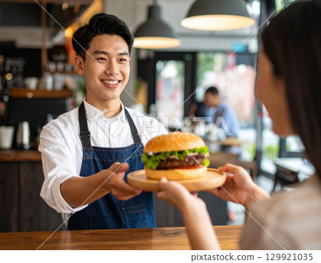 一家時尚的漢堡店，一位擁有清爽笑容的男性健美運動員為顧客服務 129921035