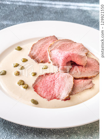 Elegant Vitello Tonnato with scattered capers and creamy sauce on plate 129921550