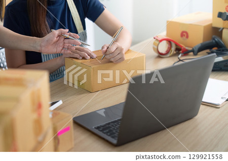 Entrepreneur collaborating on logistics with packages and laptop 129921558