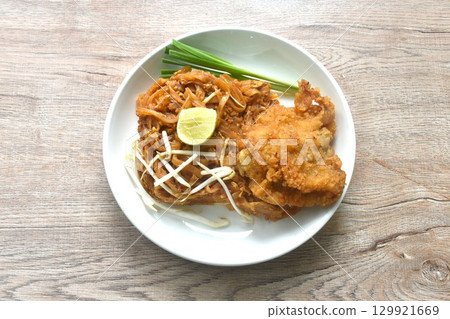 Pad Thai stir fried rice noodles with dry shrimp and egg topping crispy fried chicken on plate  129921669