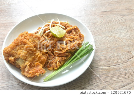 Pad Thai stir fried rice noodles with dry shrimp and egg topping crispy fried chicken on plate Pad Thai stir fried rice noodles with dry shrimp and egg topping crispy fried chicken on plate 129921670