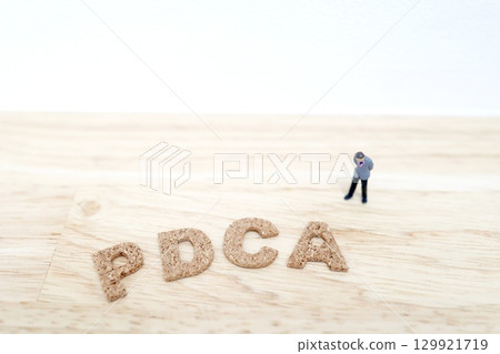 Miniature businessman and wooden letters thinking about PDCA 129921719