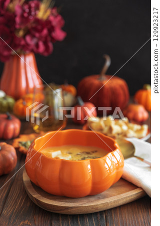Creamy pumpkin soup with croutons and seeds, served in a pumpkin-shaped bowl on dark wooden table. Creamy pumpkin soup with croutons and seeds, served in a pumpkin-shaped bowl on dark wooden table. 129923217