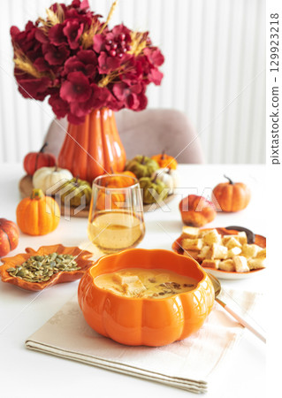 Creamy pumpkin soup with croutons and seeds, served in a pumpkin-shaped bowl on white wooden table. Creamy pumpkin soup with croutons and seeds, served in a pumpkin-shaped bowl on white wooden table. 129923218