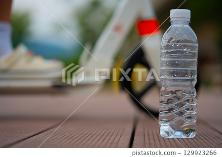 A bottle of clean water and a scooter wheel. After exercise on a summer evening. 129923266