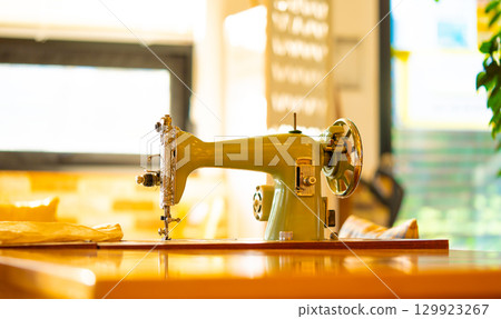 A vintage manual sewing machine on an old wooden table A vintage manual sewing machine on an old wooden table 129923267