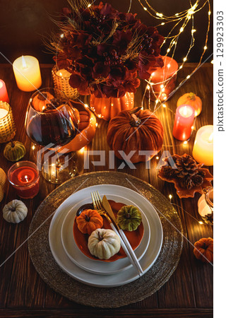 Autumnal table setting with decorative pumpkins, candles and string lights. 129923303
