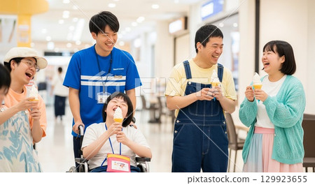 一名坐在輪椅上的殘疾男子和他的護工在購物中心微笑的照片 129923655