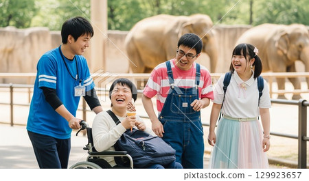 一位輪椅使用者和他的護理人員在動物園大象前微笑的照片 129923657
