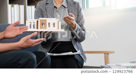 Real Estate Agent Holding Model Home During Client Meeting 129923766