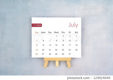 July 2026 calendar page with wooden easel, Flat lay. 129924040