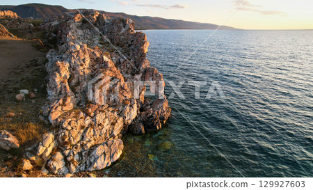 Lake Baikal at sunset. A rock with a hole in the shape of a heart on Cape Tsagan-Khushun 129927603