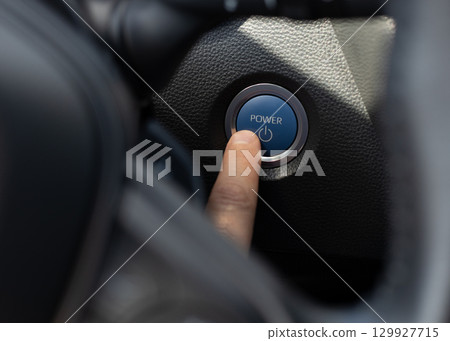 Hand pressing car start/stop power button Hand pressing car start/stop power button 129927715
