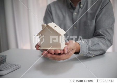 businessman holding house model with house businessman holding house model with house 129928258