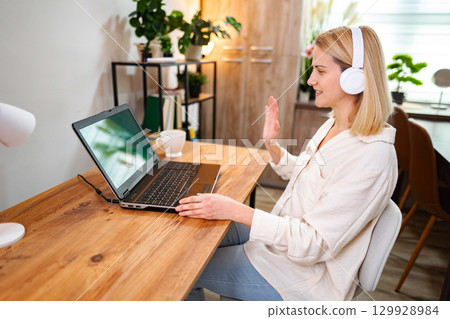 Joyful virtual meeting with a smiling young woman at home office 129928984
