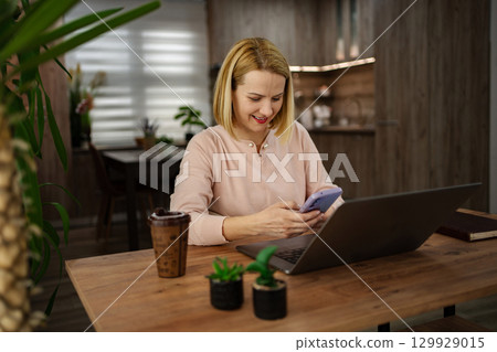 Engaging in a productive online session at a cozy home workspace with coffee and plants 129929015