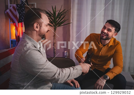 Friends celebrating a joyful moment together in a cozy living room during a fun evening gathering 129929032