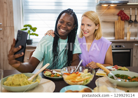Friends enjoying a joyful meal and taking selfies together Friends enjoying a joyful meal and taking selfies together 129929114