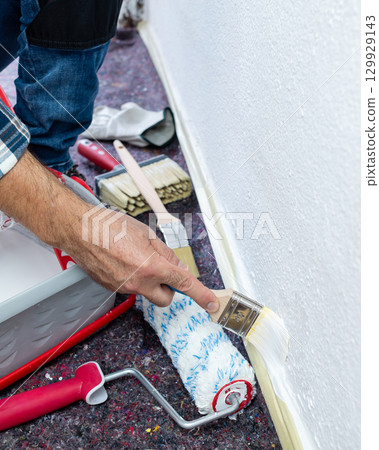 House painter worker painting a wall white. Building. House painter worker painting a wall white. Building. 129929143