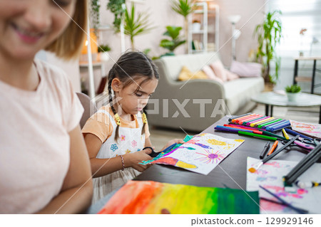 Mother and daughter engage in creative arts and crafts at home during a sunny afternoon 129929146