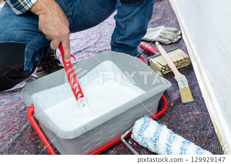 House painter worker prepares white paint. Building. 129929147