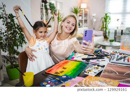 Mother and daughter enjoy a creative art session at home, capturing a joyful selfie Mother and daughter enjoy a creative art session at home, capturing a joyful selfie 129929161