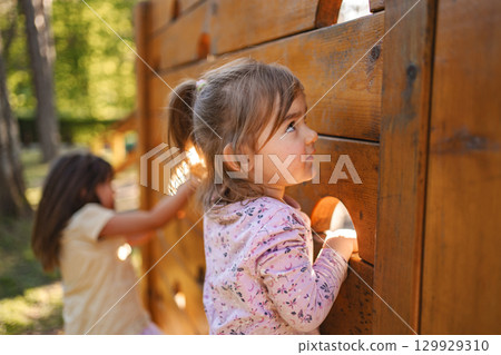 Little cute girl is climbing on the playground 129929310