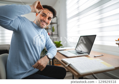 Portrait of smiling man at desk and laptop Portrait of smiling man at desk and laptop 129929318