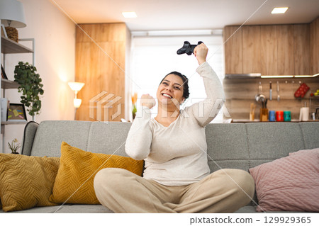 Woman having fun playing video games at home 129929365