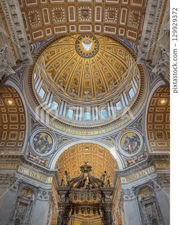 Ornate, gilded dome and ceiling of St. Peter's Basilica, features a golden sunburst design, decorated with intricate mosaics and paintings. Luxurious decoration of the Vatican iconic interior 129929372