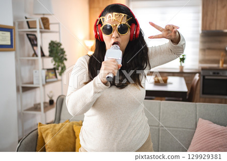 Woman with wireless headphones singing karaoke at home Woman with wireless headphones singing karaoke at home 129929381