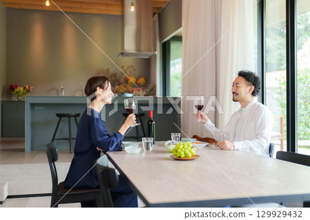 A couple drinking red wine in a modern living/dining room 129929432
