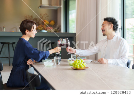 A couple drinking red wine in a modern living/dining room A couple drinking red wine in a modern living/dining room 129929433