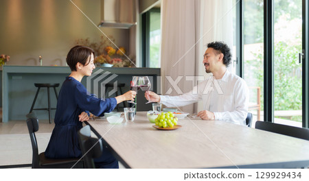 A couple drinking red wine in a modern living/dining room A couple drinking red wine in a modern living/dining room 129929434