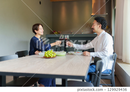 A couple drinking red wine in a modern living/dining room 129929436