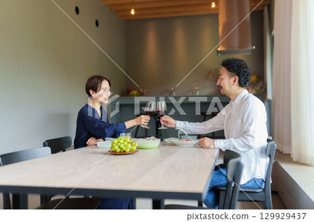 A couple drinking red wine in a modern living/dining room 129929437