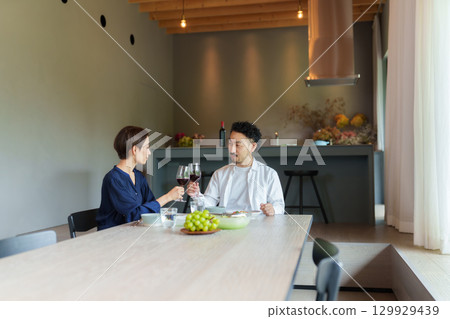 A couple drinking red wine in a modern living/dining room A couple drinking red wine in a modern living/dining room 129929439