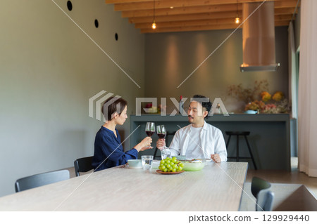 A couple drinking red wine in a modern living/dining room A couple drinking red wine in a modern living/dining room 129929440