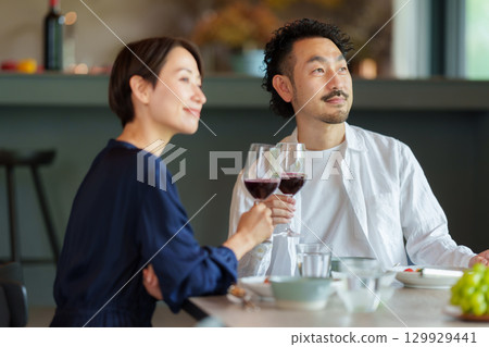 A couple drinking red wine in a modern living/dining room 129929441