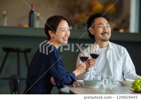 A couple drinking red wine in a modern living/dining room 129929445