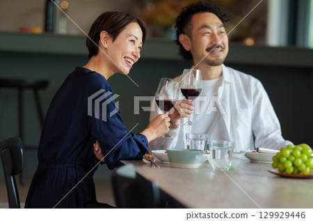 A couple drinking red wine in a modern living/dining room 129929446