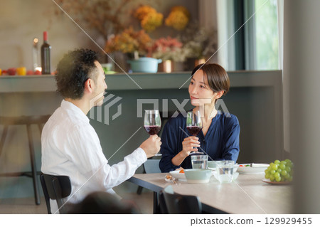 A couple drinking red wine in a modern living/dining room A couple drinking red wine in a modern living/dining room 129929455