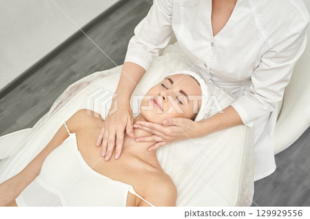Caucasian young female receiving facial massage from therapist in spa 129929556