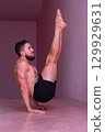 Man performs advanced core balance on hands with legs extended. Concept of strength, stability, discipline, control, endurance and physical mastery. 129929631