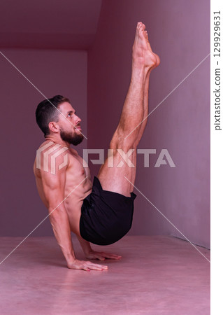 Man performs advanced core balance on hands with legs extended. Concept of strength, stability, discipline, control, endurance and physical mastery. 129929631