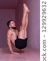 Athletic man holds advanced core balance on hands with legs lifted. Concept of strength, focus, discipline, control, endurance and body mastery. 129929632