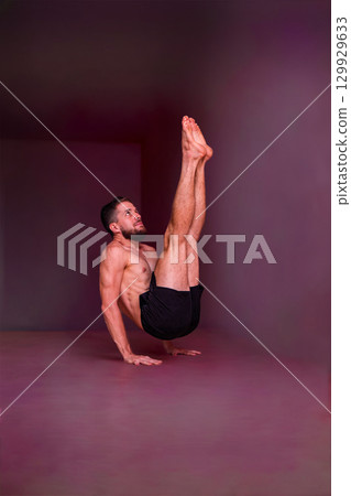 Man holds advanced balance pose on hands with straight lifted legs. Concept of strength, balance, focus, endurance, discipline and physical mastery. 129929633